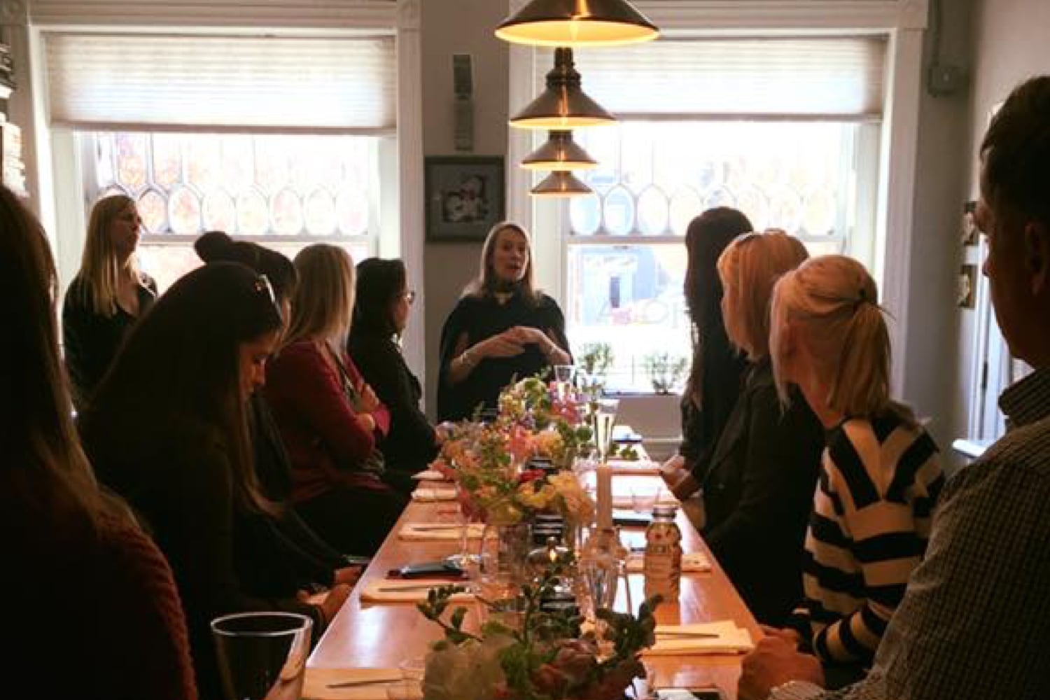 Charm City Beverage staff gathered around a dinner table listening to a speaker